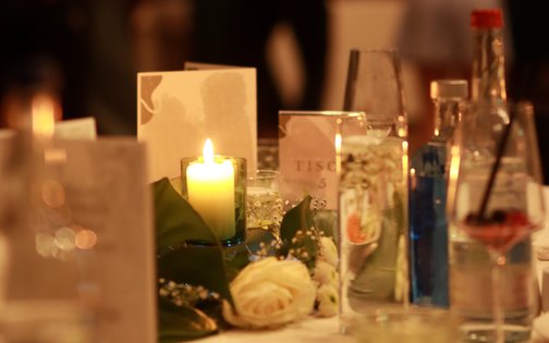 Stimmungsvoll beleuchteter Tisch mit Kerze, Blumenschmuck und Gläsern bei einer Feier im Park-Hotel Hagenbeck in Hamburg